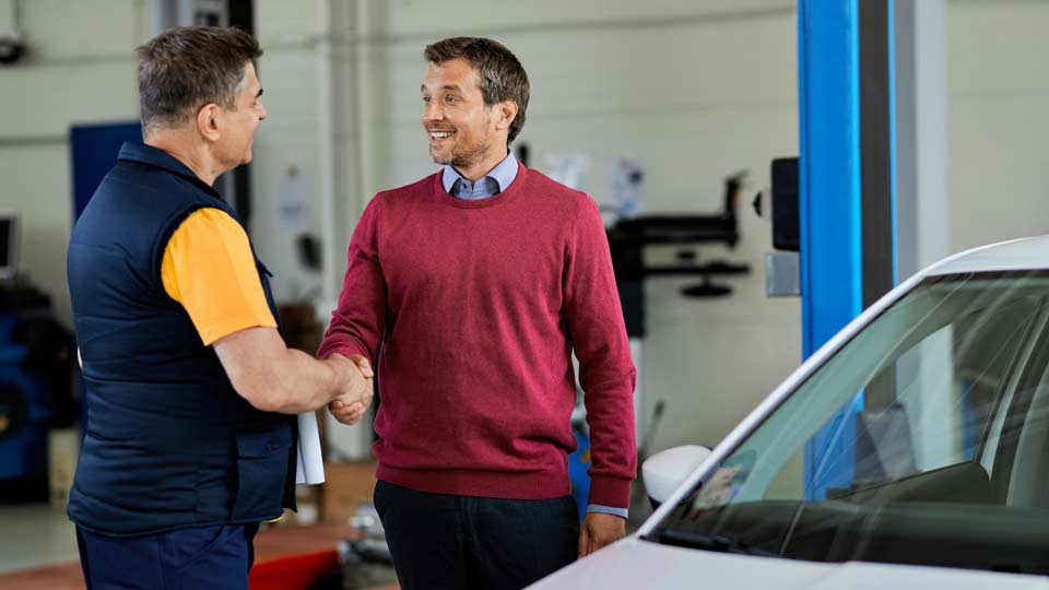 Seriöser Autoexport-Händler und Kunde beim Fahrzeugverkauf mit Exportkennzeichen und Dokumenten